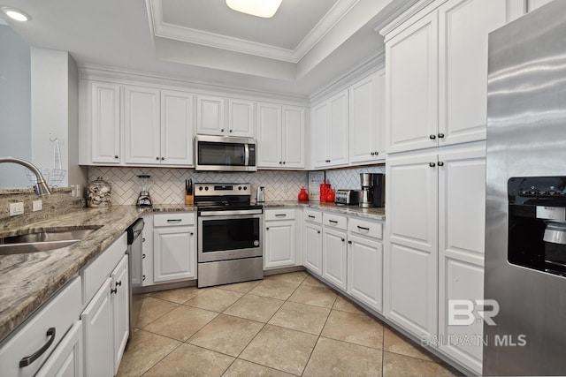 25494 Perdido Beach Blvd Unit 2005, Orange Beach, AL 36561 - kitchen featuring appliances with stainless steel finishes, white cabinetry, a sink, a tray ceiling, and light tile patterned flooring