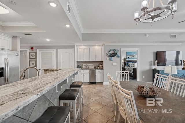25494 Perdido Beach Blvd Unit 2005, Orange Beach, AL 36561 - kitchen with visible vents, stainless steel fridge, white cabinets, light stone counters, and light tile patterned floors