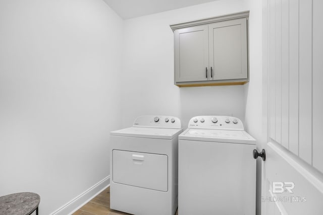 laundry room with cabinets, light hardwood / wood-style flooring, and washing machine and clothes dryer