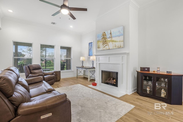 living room with ceiling fan, light wood-type flooring, and ornamental molding