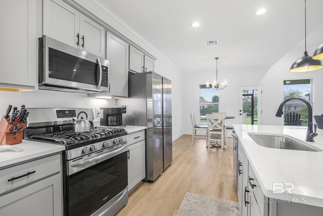 kitchen featuring appliances with stainless steel finishes, gray cabinetry, sink, pendant lighting, and a chandelier