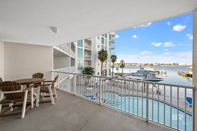 balcony featuring a community hot tub, a water view, and a patio