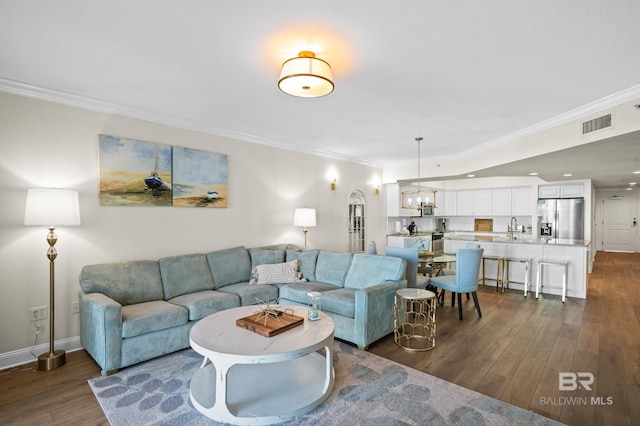 living room with sink, a chandelier, ornamental molding, and dark hardwood / wood-style floors