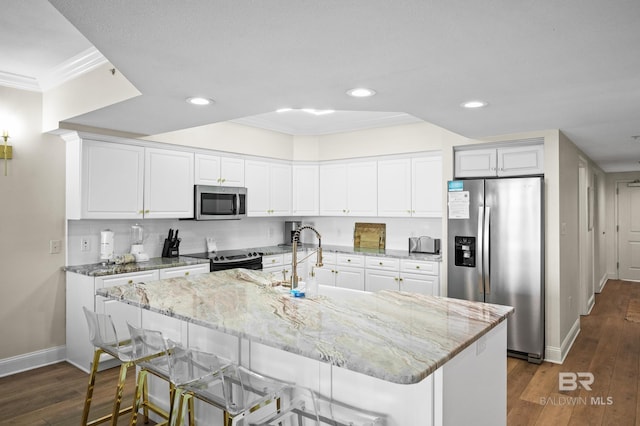 kitchen featuring a center island with sink, white cabinets, a breakfast bar, and stainless steel appliances