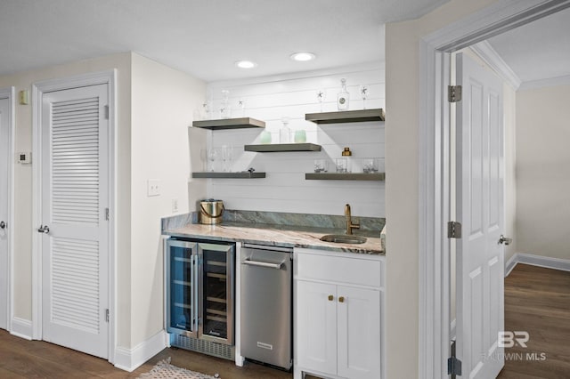 bar with white cabinetry, sink, light stone counters, dark hardwood / wood-style floors, and beverage cooler