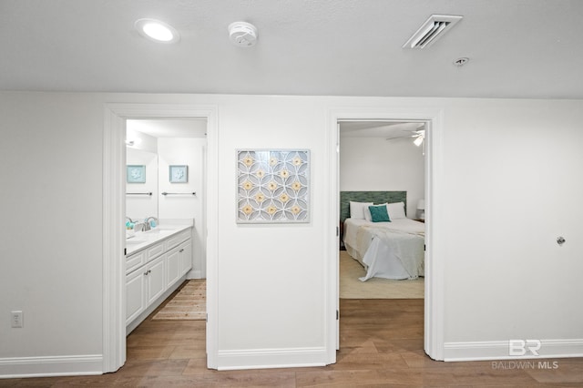 corridor with hardwood / wood-style flooring and sink