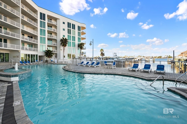 view of swimming pool with pool water feature and a water view