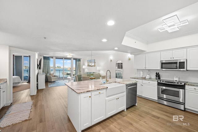 kitchen with a kitchen island with sink, sink, white cabinets, light wood-type flooring, and stainless steel appliances