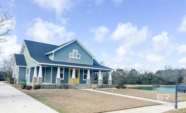 view of front of home with a front yard, a water view, and covered porch