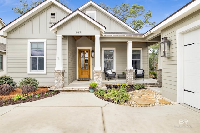 view of exterior entry featuring a garage, a porch, and board and batten siding