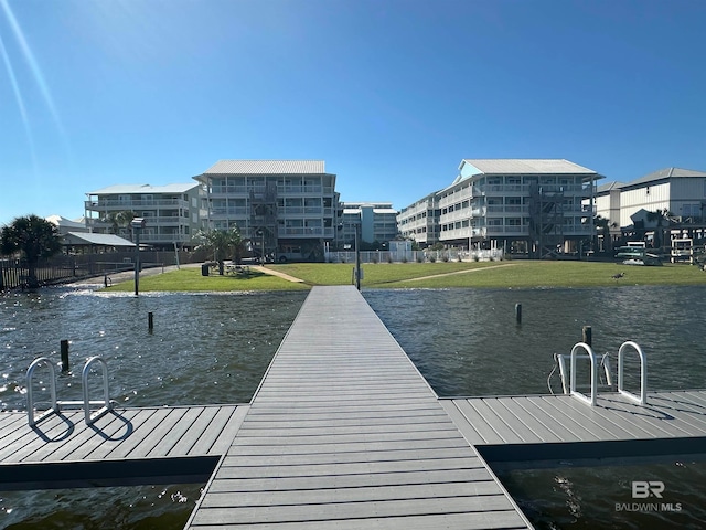 view of dock with a water view and a lawn