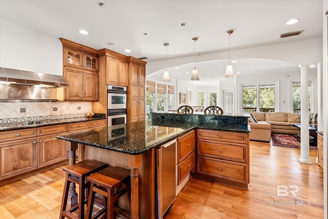 kitchen with decorative columns, brown cabinetry, visible vents, and appliances with stainless steel finishes