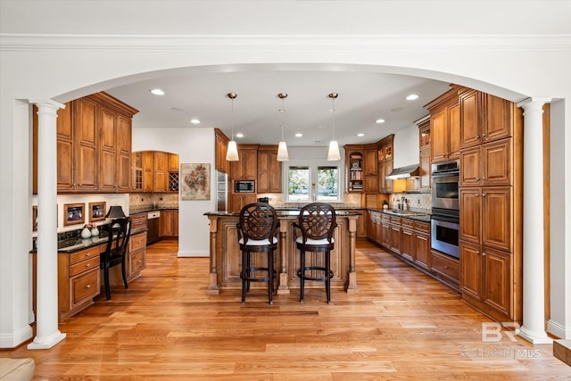 kitchen with a breakfast bar, decorative columns, brown cabinets, and stainless steel appliances