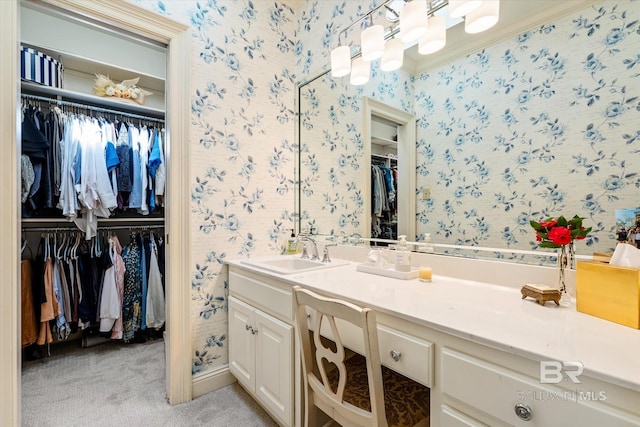 bathroom with a walk in closet, wallpapered walls, vanity, and ornamental molding