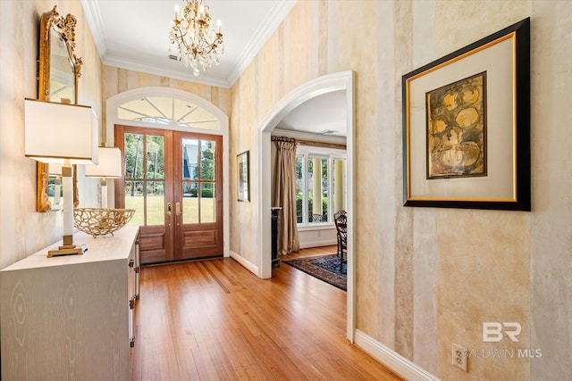 foyer entrance featuring baseboards, ornamental molding, hardwood / wood-style flooring, french doors, and a chandelier