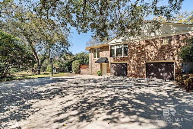 view of home's exterior with a garage, brick siding, and driveway