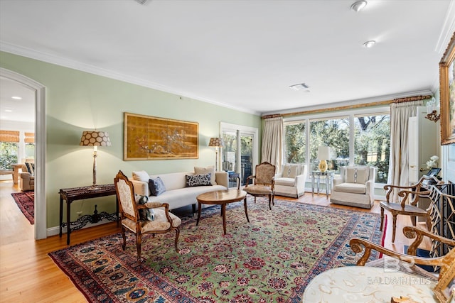 living room featuring light wood-style floors, a healthy amount of sunlight, and ornamental molding