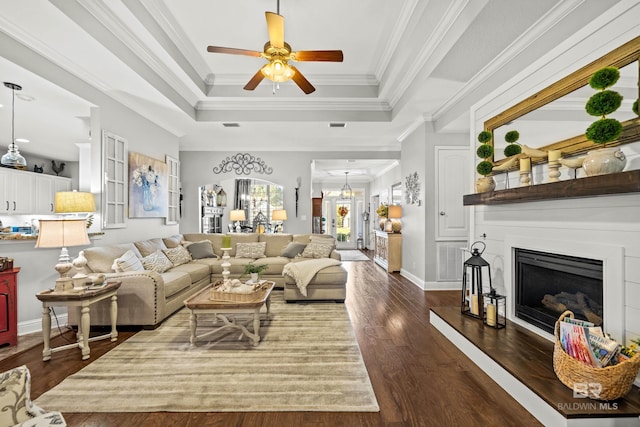 living room with a tray ceiling, ceiling fan, dark wood-type flooring, and ornamental molding