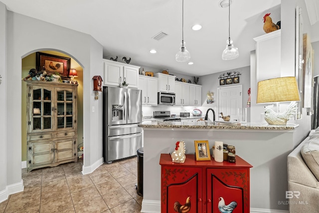 kitchen with light stone countertops, appliances with stainless steel finishes, white cabinetry, and hanging light fixtures