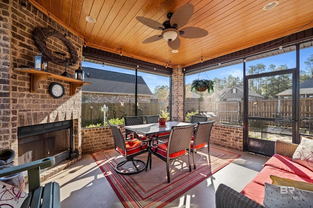 sunroom / solarium featuring an outdoor brick fireplace, ceiling fan, and wood ceiling