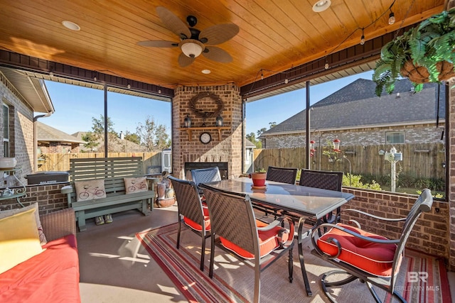 sunroom / solarium with ceiling fan, wood ceiling, and a fireplace