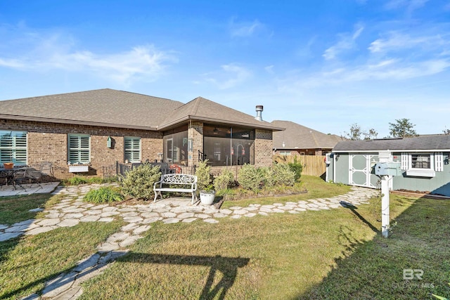 rear view of property featuring a lawn, a patio area, and a storage shed