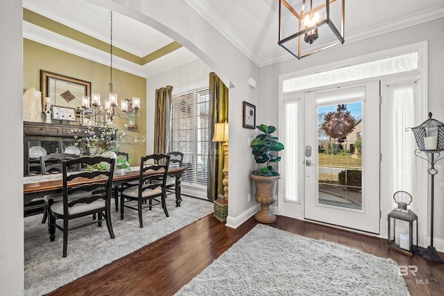 foyer entrance with dark hardwood / wood-style flooring, ornamental molding, and a notable chandelier