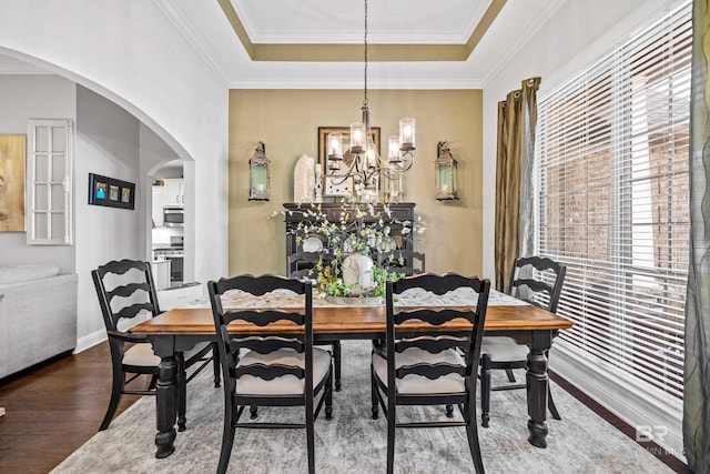 dining room with hardwood / wood-style floors, ornamental molding, a tray ceiling, and a chandelier