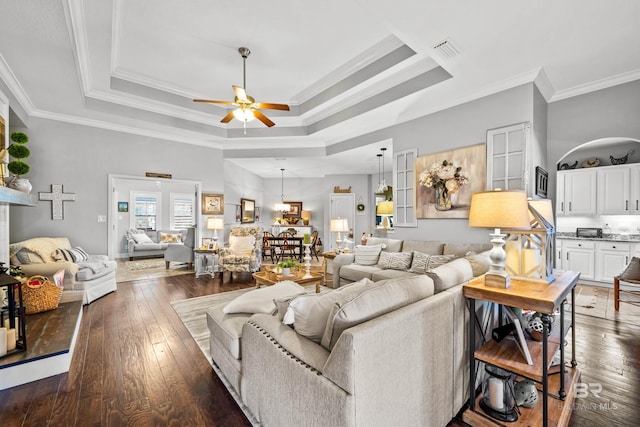 living room featuring dark hardwood / wood-style flooring, a raised ceiling, ceiling fan, and ornamental molding