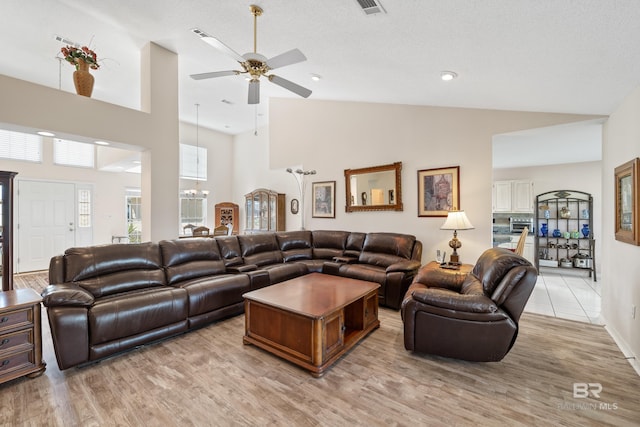 living area featuring ceiling fan with notable chandelier, high vaulted ceiling, and light wood finished floors