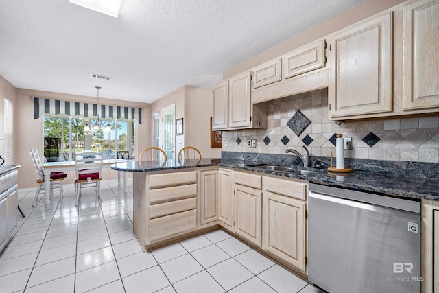 kitchen with pendant lighting, light tile patterned floors, a sink, dark stone countertops, and dishwasher