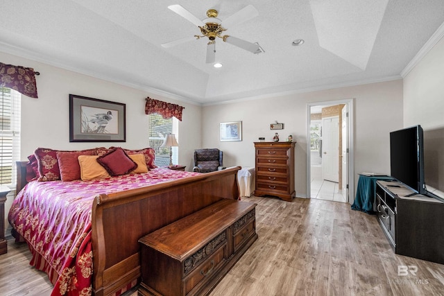 bedroom with light wood-style floors, a textured ceiling, ornamental molding, and a tray ceiling