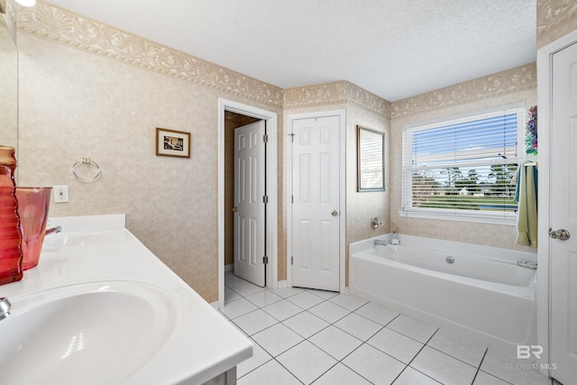 full bathroom featuring tile patterned flooring, a garden tub, a sink, and a textured ceiling