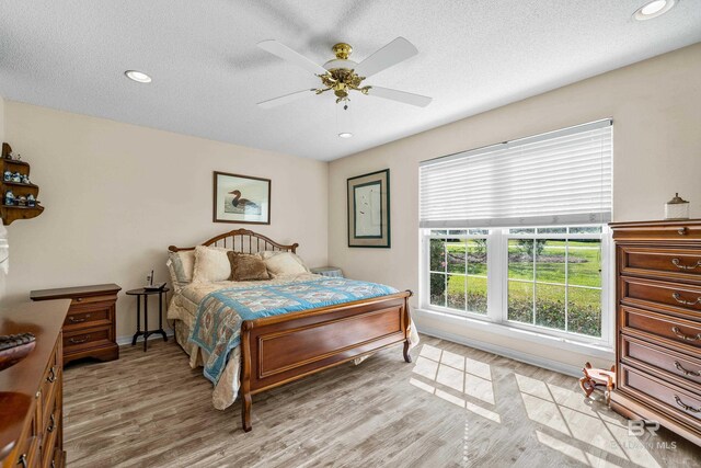 bedroom with a textured ceiling, ceiling fan, light wood-style flooring, recessed lighting, and baseboards