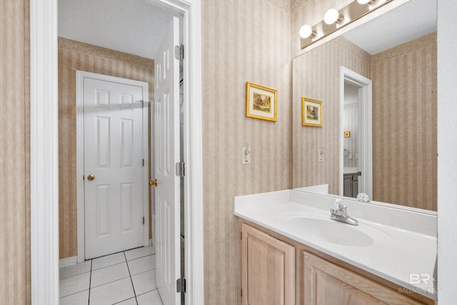 bathroom with tile patterned flooring, vanity, a textured ceiling, and wallpapered walls