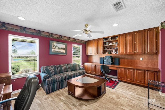 office featuring light wood-style flooring, plenty of natural light, built in study area, and visible vents