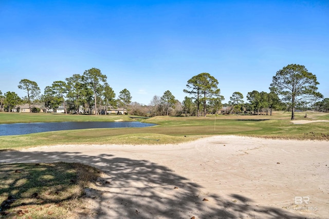 view of home's community with a water view, a lawn, and golf course view