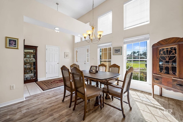 dining area with a chandelier, a high ceiling, light wood-style flooring, and baseboards