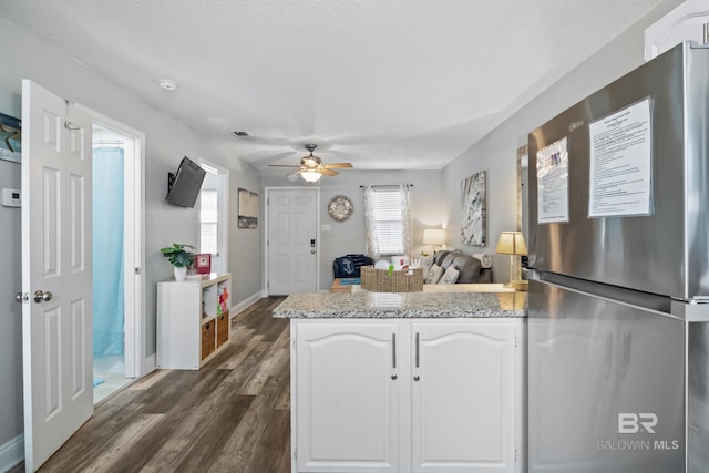 kitchen featuring a ceiling fan, baseboards, dark wood finished floors, freestanding refrigerator, and white cabinetry