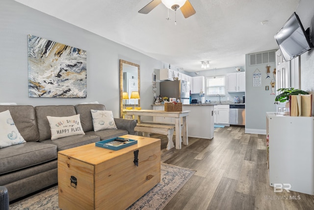 living room featuring ceiling fan, light hardwood / wood-style floors, and sink