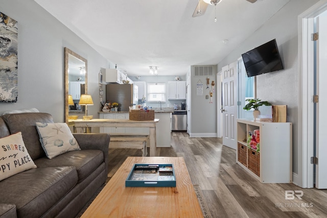 living room with visible vents, ceiling fan, baseboards, and wood finished floors