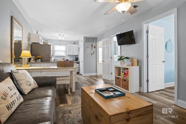 living room with visible vents, ceiling fan, baseboards, and wood finished floors