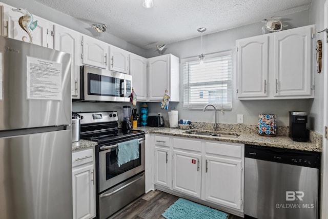 kitchen featuring a sink, a textured ceiling, dark wood-style floors, stainless steel appliances, and white cabinets