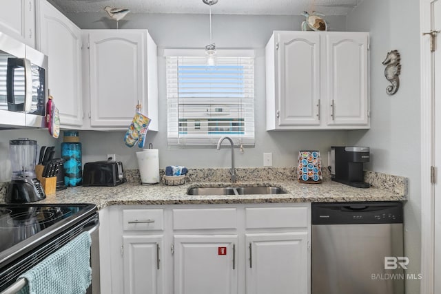 kitchen featuring light stone counters, white cabinets, stainless steel appliances, and a sink