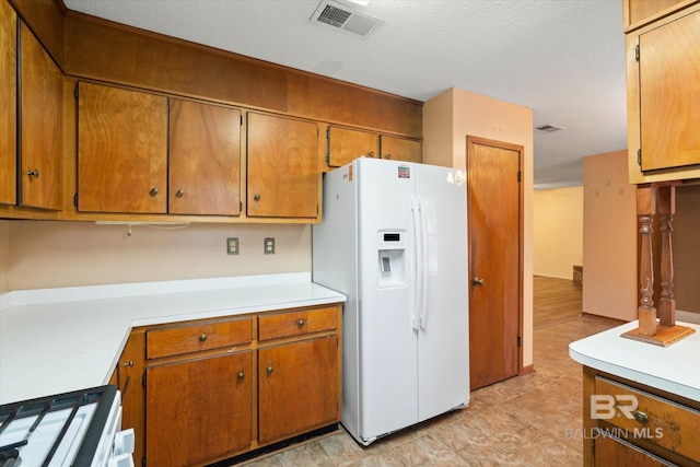 2405 Pavan Dr, Mobile, AL 36693 - kitchen with light countertops, visible vents, brown cabinetry, and white appliances