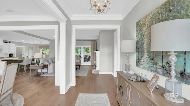 entryway featuring a notable chandelier, light hardwood / wood-style flooring, and ornamental molding