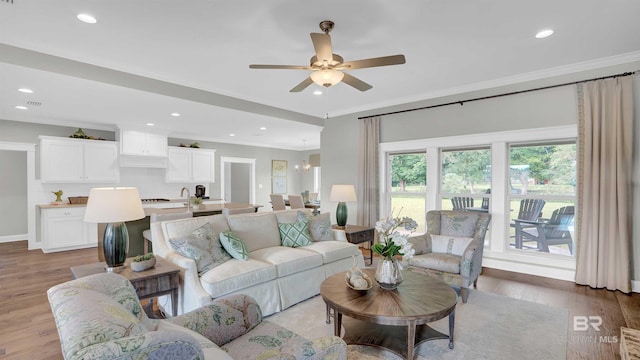 living room with crown molding, ceiling fan, and light wood-type flooring