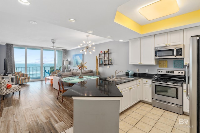 kitchen with white cabinetry, stainless steel appliances, sink, and kitchen peninsula