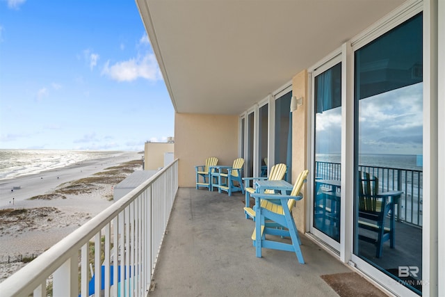 balcony featuring a view of the beach and a water view