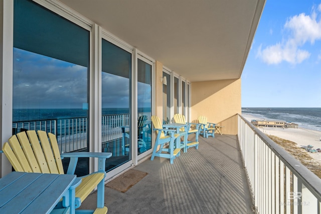balcony with a water view and a view of the beach